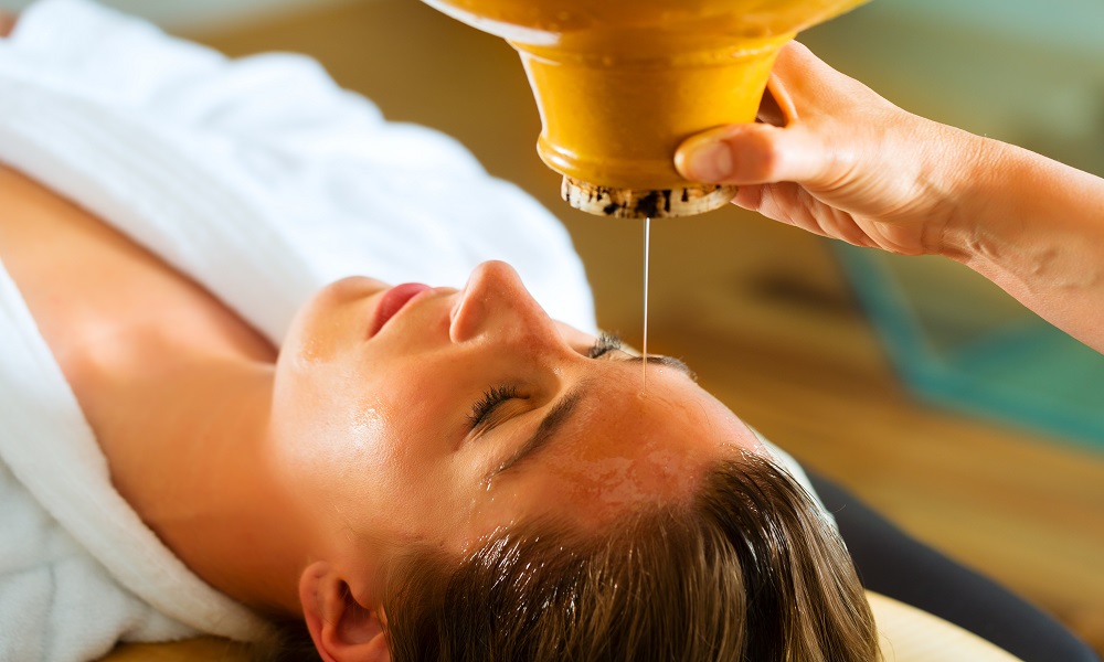 Warm oil poured in a steady stream over the forehead
