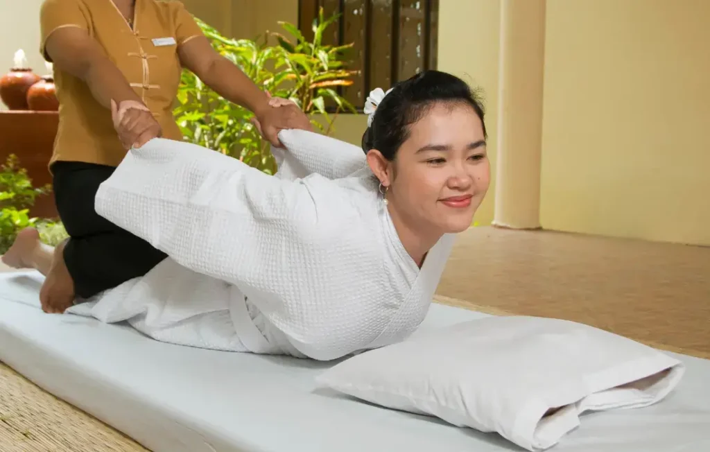 Guest being stretched on a treatment bed beside hot stones
