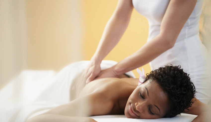 Guest being stretched on a treatment bed beside hot stones