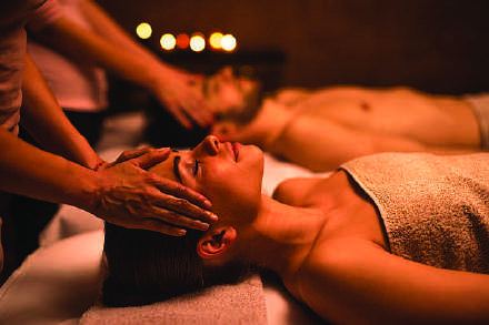 Two guests receiving therapy side by side in a candlelit room